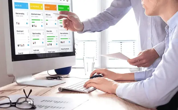 two co-workers pointing at charts on a screen